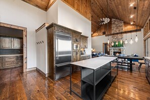 Une cuisine moderne avec des meubles en bois, un réfrigérateur en acier inoxydable et un coin repas doté d’une longue table.