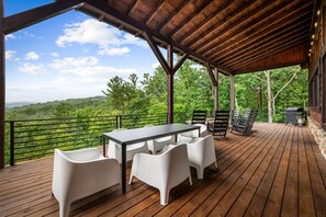 Une terrasse extérieure avec une table et des chaises, un barbecue et une vue sur un paysage boisé.