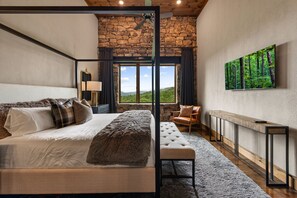 Une chambre à coucher comprenant un lit, une chaise, un banc, une cheminée et une grande fenêtre donnant sur un beau paysage.