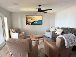 Ein Wohnzimmer mit Deckenventilator, zwei Sesseln, einer Couch und einem Couchtisch.