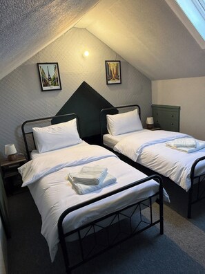 A room with two twin beds, a nightstand with a lamp, and a green dresser. - Large Private Suite for Families & Workers Near Hospital (Greater London)