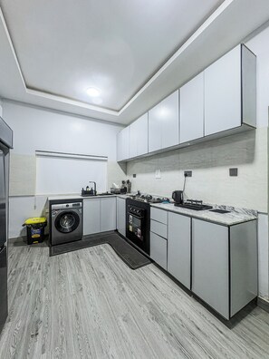Eine moderne Küche mit Einbauwaschmaschine, Backofen und einer Marmorarbeitsplatte.