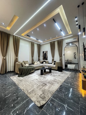 A modern living room with a sectional sofa, a coffee table, and a large mirror. - Swan Luxury Homes | Luxury 2-Bedroom Shortlet Apartment, Wuye, Abuja (Abuja)