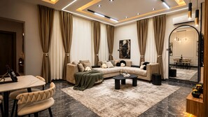 A modern living room with a sectional sofa, a dining table, and a coffee table. - Swan Luxury Homes | Luxury 2-Bedroom Shortlet Apartment, Wuye, Abuja (Abuja)