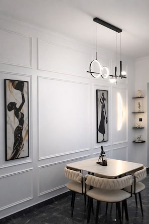 A dining area with a round table, four chairs, and a pendant light fixture. - Swan Luxury Homes | Luxury 2-Bedroom Shortlet Apartment, Wuye, Abuja (Abuja)