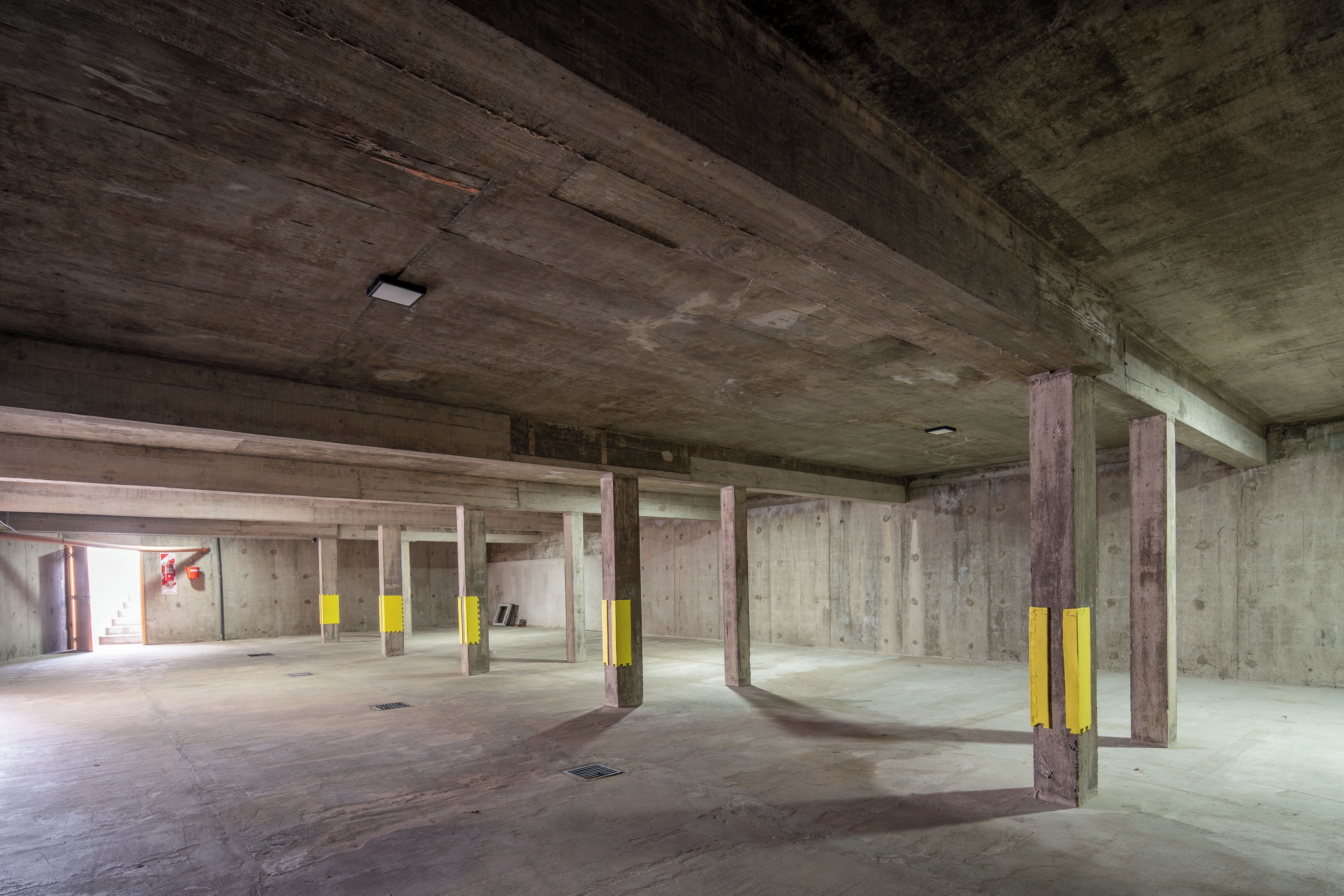 An unfinished interior with concrete pillars and a high ceiling.