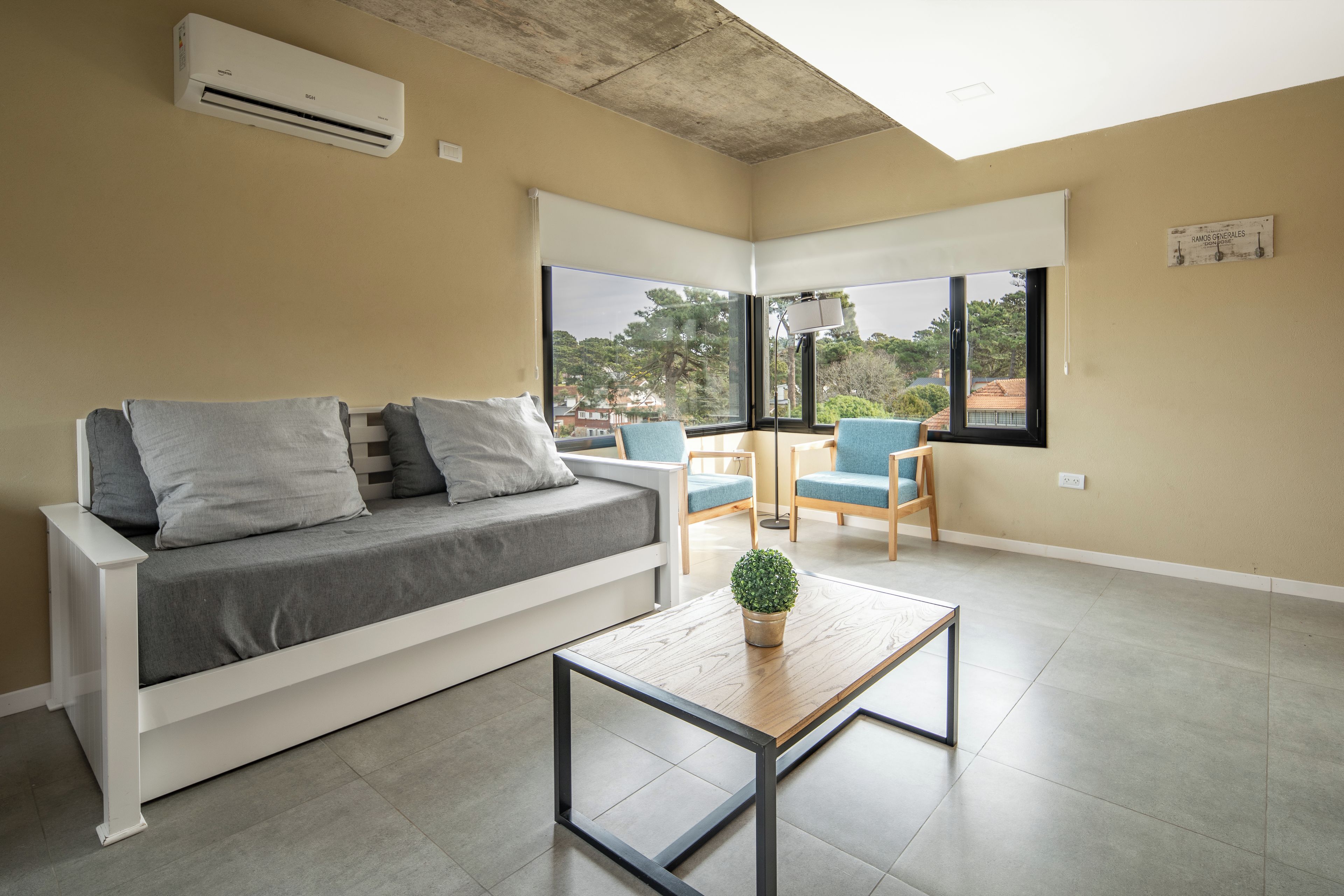 Sala de estar moderna com sofá, poltronas, mesa de centro e vista para o exterior.