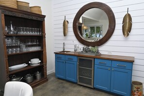 A kitchen with a wooden cabinet, a round mirror, and a blue countertop. - Private Estate with Pool & Two Pickleball Courts Directly on Twin Coves Beach (Governor's Harbour)