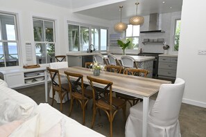 A modern kitchen with a dining area, large windows, and a view of the ocean. - Private Estate with Pool & Two Pickleball Courts Directly on Twin Coves Beach (Governor's Harbour)