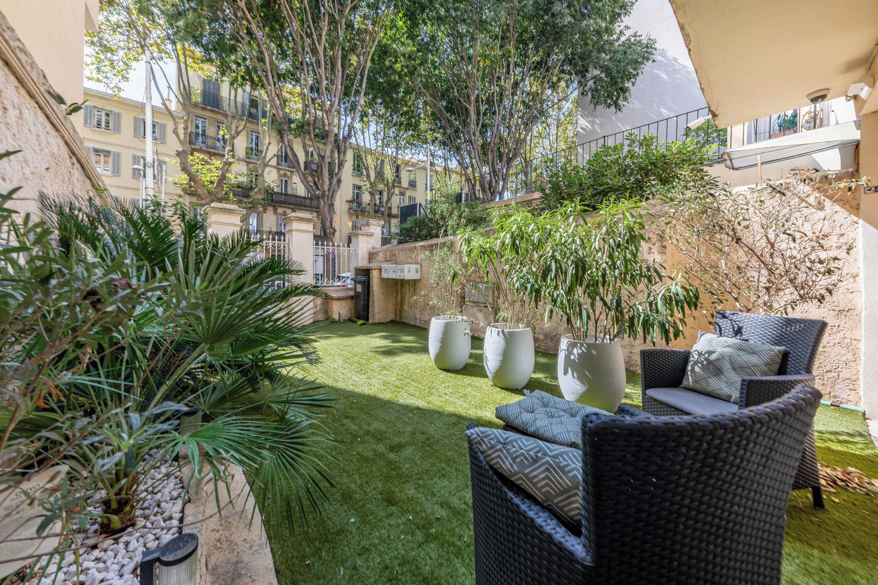A courtyard with a grassy area, outdoor furniture, and potted plants.