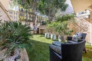 A courtyard with a grassy area, outdoor furniture, and potted plants. - L' Azur du Mourillon 5 minutes from the beach - Welkeys (Toulon)