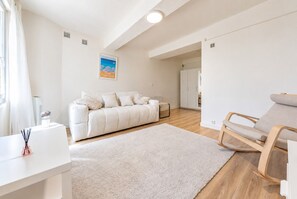 A modern living room with a sofa, a chair, a white rug, and a painting on the wall. - L' Azur du Mourillon 5 minutes from the beach - Welkeys (Toulon)