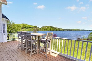Une terrasse en bois avec une table et des chaises donnant sur un lac.