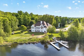 A large white house with a large lawn and a dock extending into a lake. - Spacious 5-bedroom house with Hot Tub, Sauna, Steam Room, Bar, Gym,& Family Fun (Michigamme)