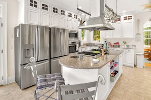 A modern kitchen with stainless steel appliances, a granite countertop island, and white cabinetry. - Spacious 5-bedroom house with Hot Tub, Sauna, Steam Room, Bar, Gym,& Family Fun (Michigamme)