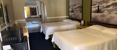 A hotel room with two beds, a television, and artwork on the walls.