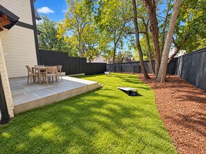 Ein Garten mit Terrasse, Rasen und Holzzaun.