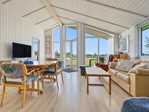 A spacious living room with a wooden floor, a dining area with a table and chairs, a sofa, and a television. - "Sighrik" - 600m from the sea by Interhome (Stubbekøbing)
