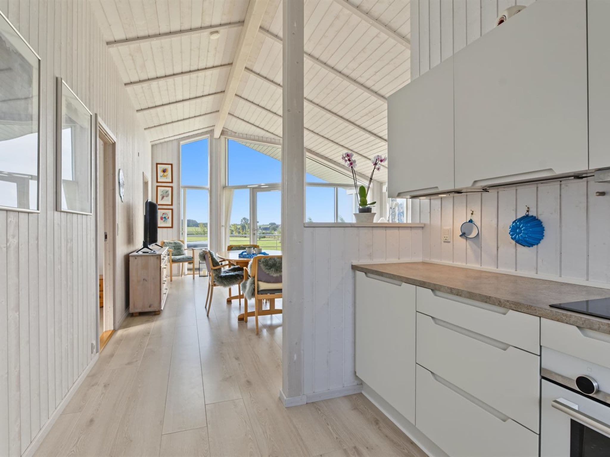 A spacious kitchen with a high ceiling, large windows, and a view of the outdoors.