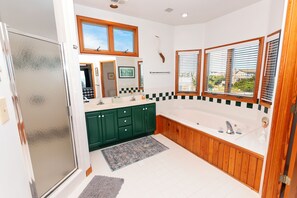 A modern bathroom with a freestanding bathtub, green cabinets, and a large mirror. - Semi-Oceanfront- Private Pool, Hot Tub-OH1200, Spyglass (Corolla)