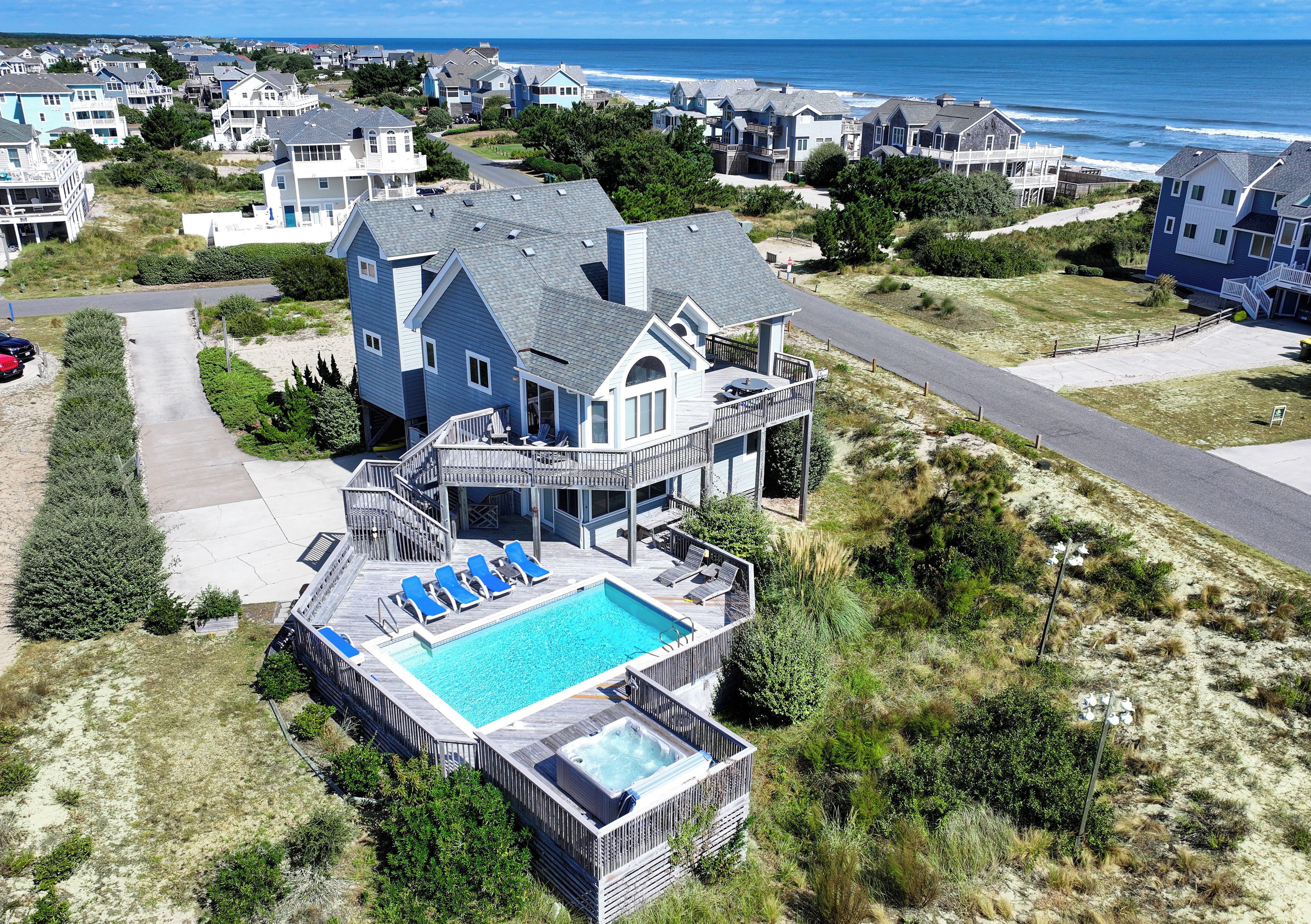 A large house with a swimming pool, multiple balconies, and a view of the ocean.