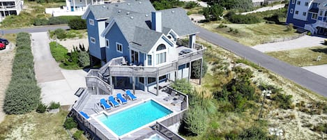 A large house with a swimming pool, multiple balconies, and a view of the ocean.