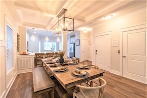 A dining area with a wooden table set for four, a chandelier, and a view into the kitchen. - Free 6-Seat Golf Cart | Private Free Heated Pool | Walk to Beach | Sleeps 18 (Hilton Head Island)