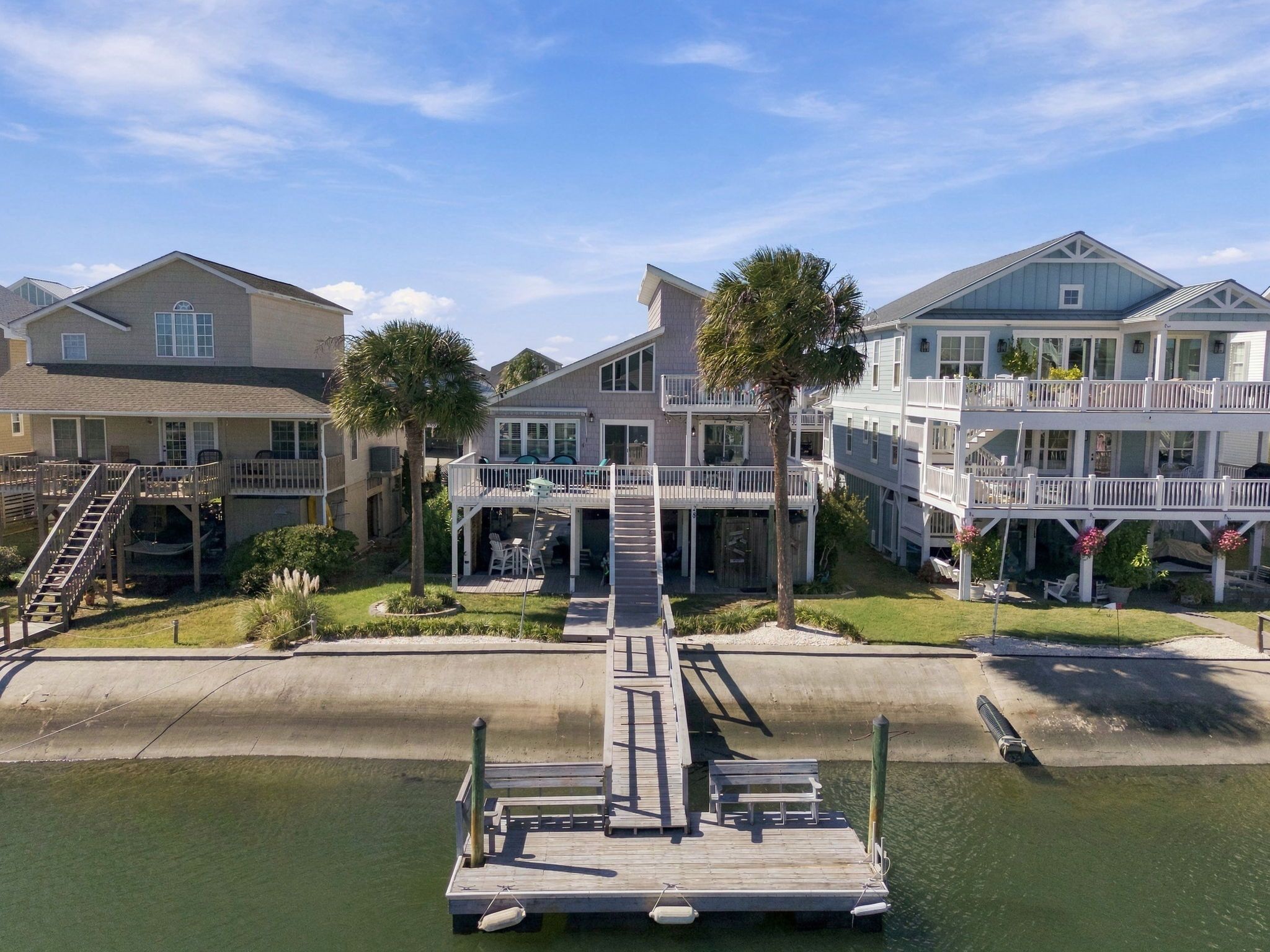 A waterfront property with a dock, multiple-story buildings, and a grassy area.
