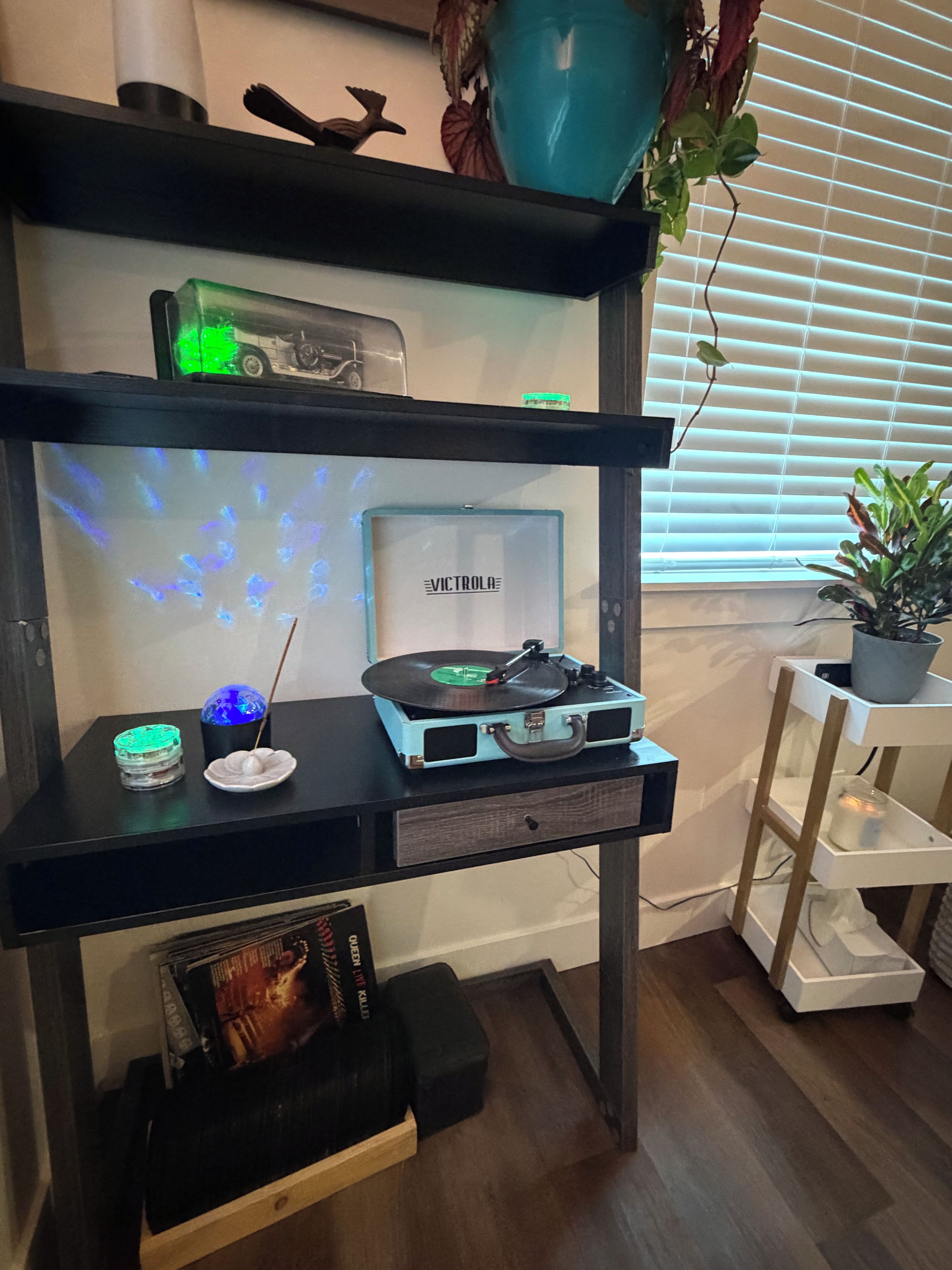 A room with a black desk featuring a turntable, incense, and a decorative globe.