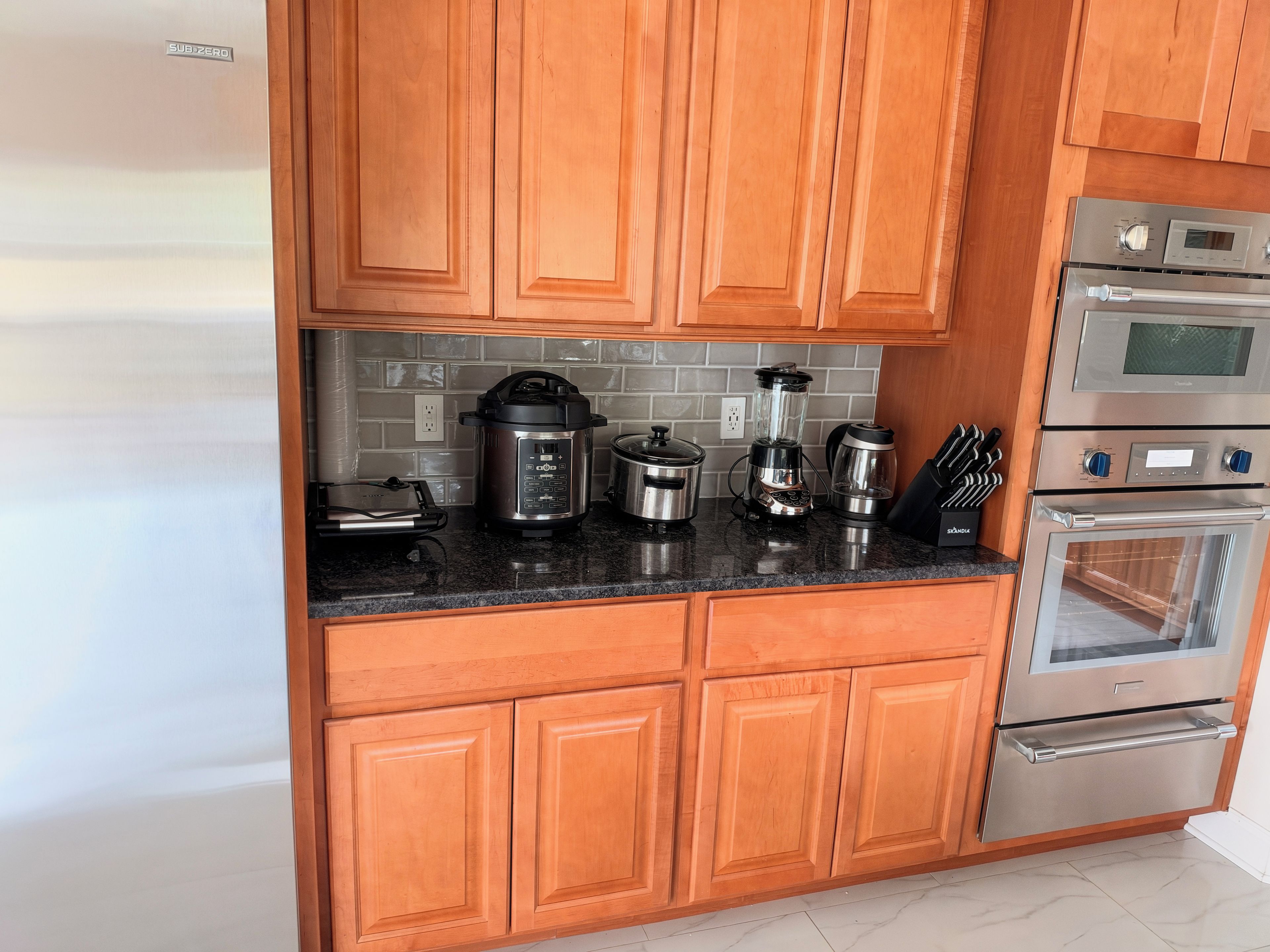 A kitchen with wooden cabinets, a stainless steel range, and various appliances including a blender and a slow cooker.