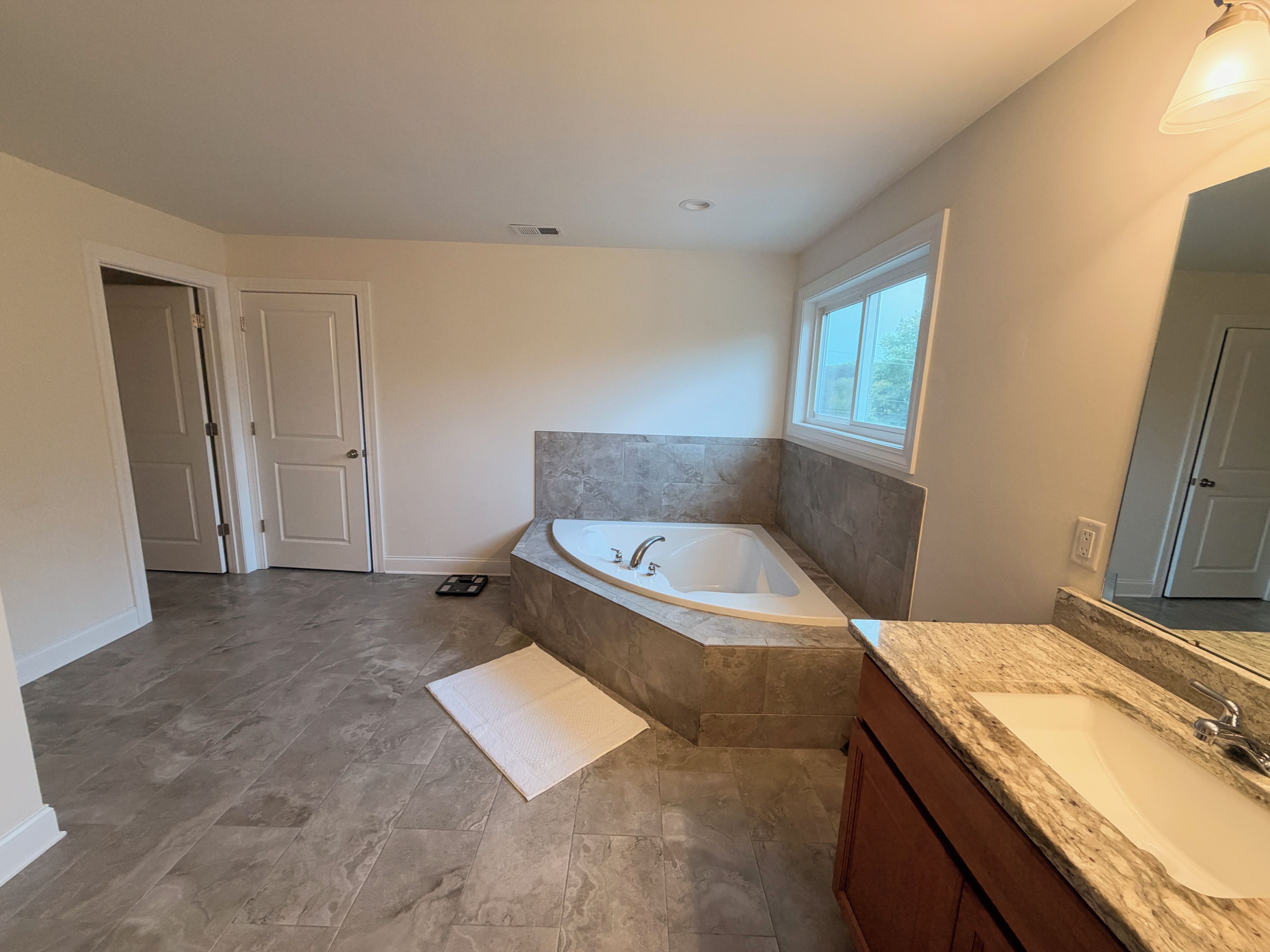 A bathroom with a freestanding bathtub, a vanity with a sink, and a window providing natural light.