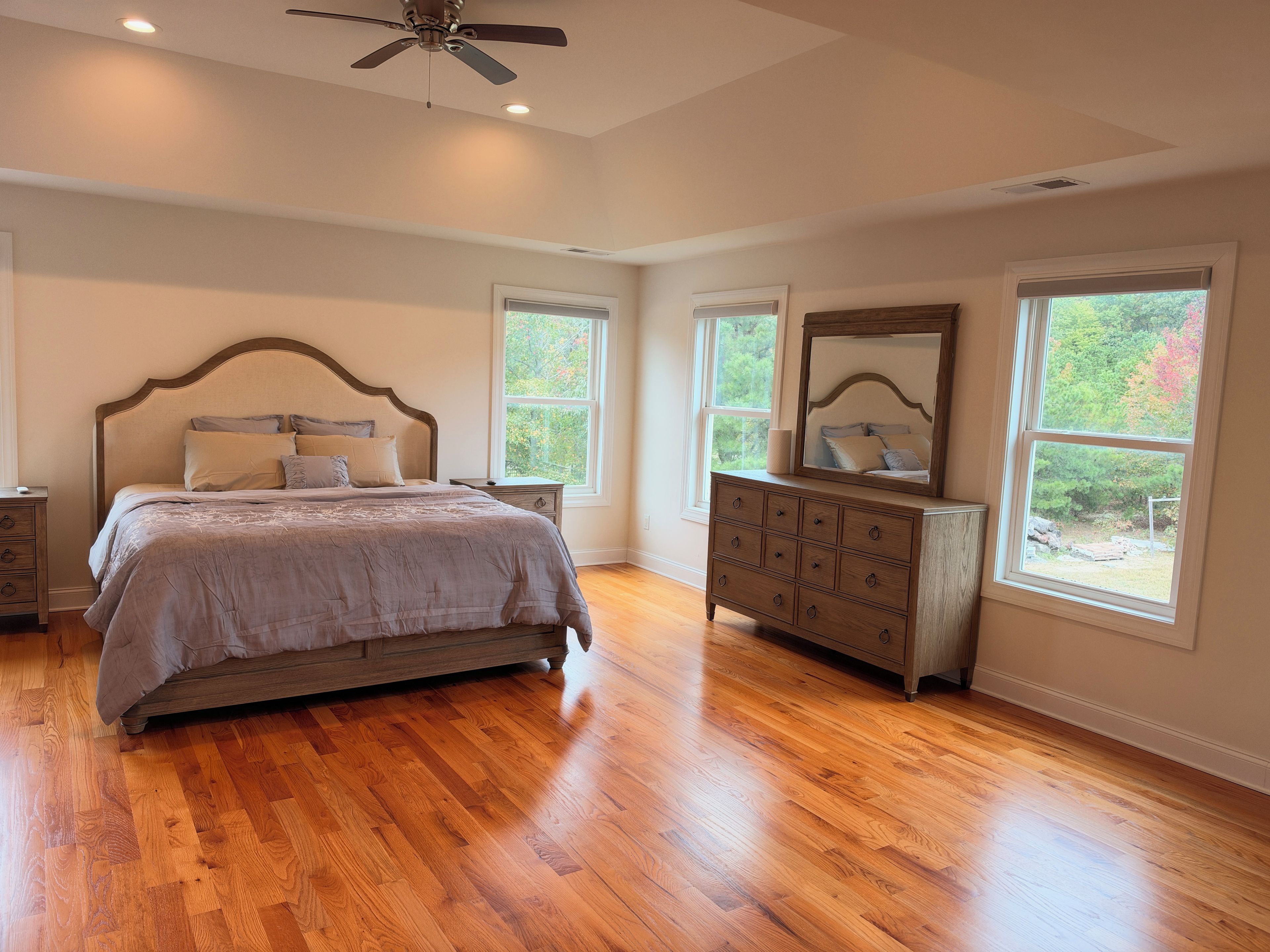 A bedroom with a bed, dresser, and two windows.
