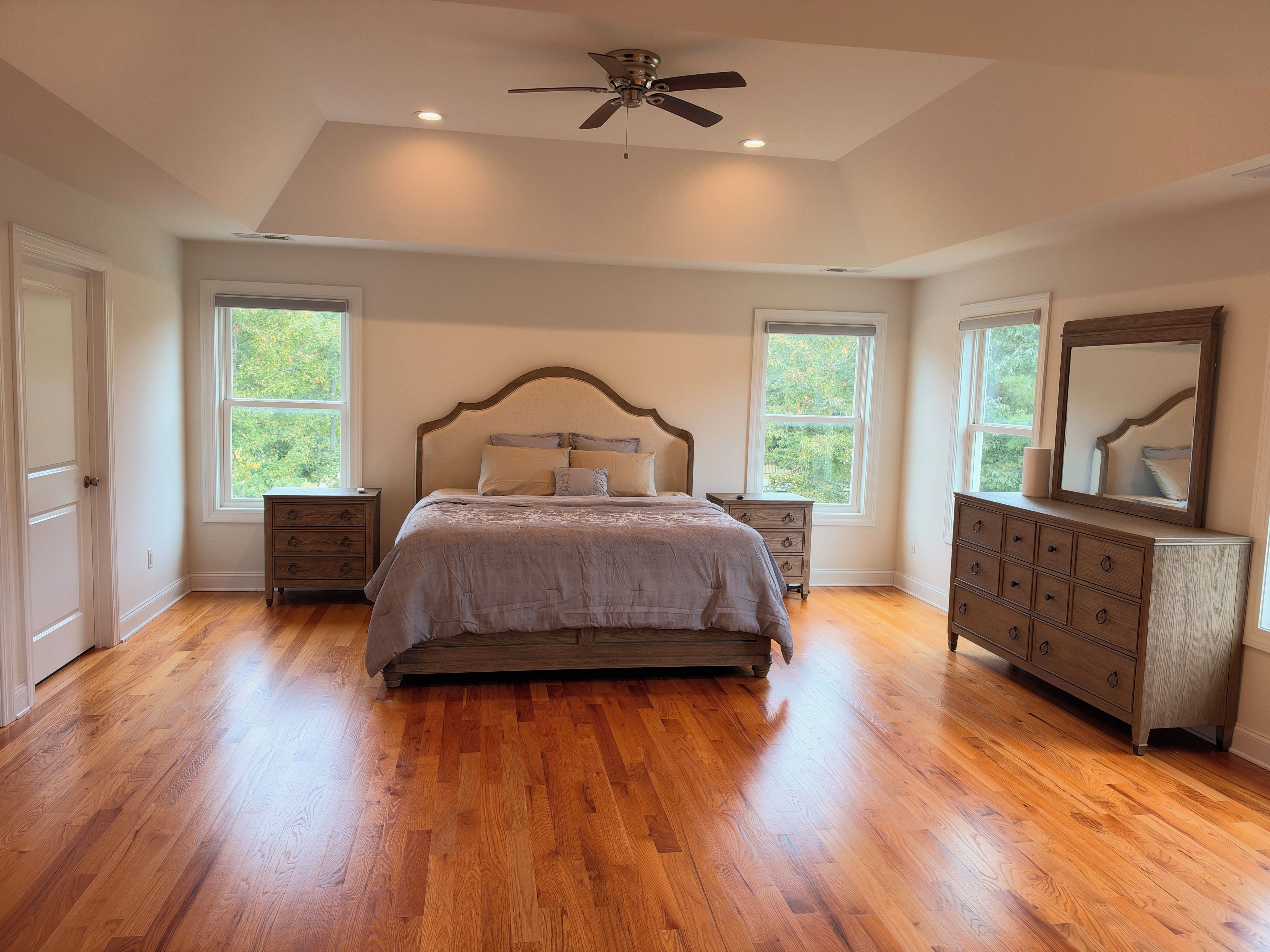 A bedroom with a bed, dresser, nightstands, and a ceiling fan.