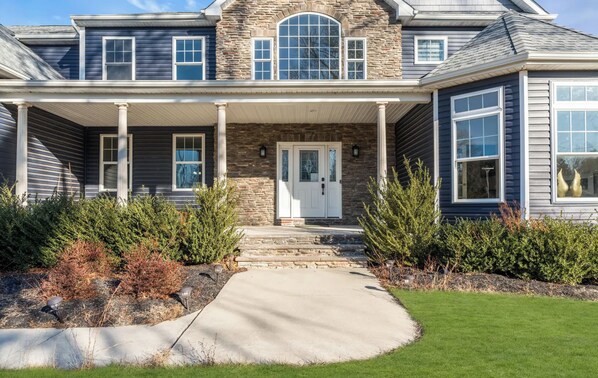 A two-story house with a stone facade, a covered front porch, and a well-maintained lawn.