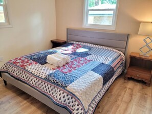 A neatly made bed with a quilt, two bedside tables, a lamp, and a window with a view. - Fall Escape at Spanish Style 4br/3ba home! (Niceville)