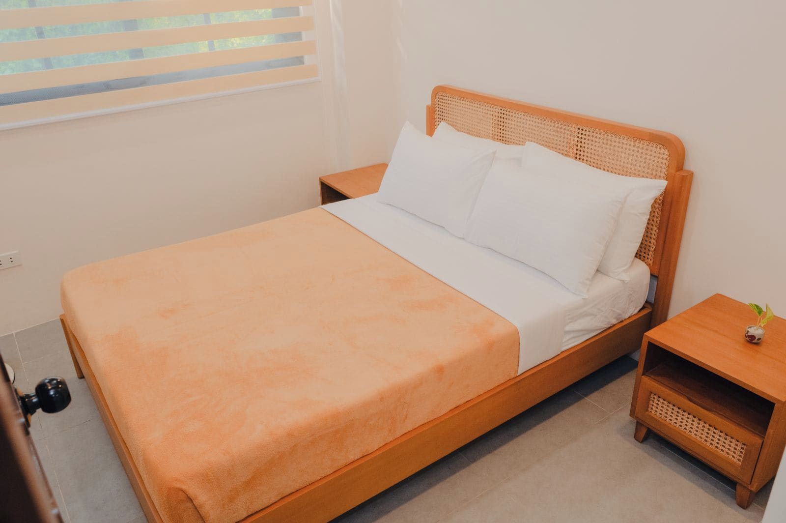 A single bed with a wooden frame and a white mattress, accompanied by two nightstands with woven side tables.