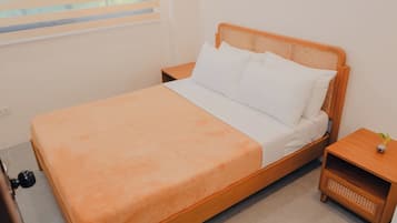 A single bed with a wooden frame and a white mattress, accompanied by two nightstands with woven side tables.