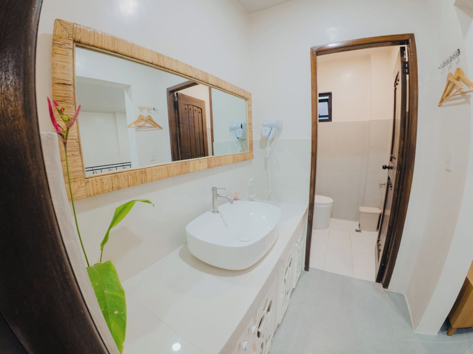 Un baño con un lavamanos blanco, un espejo grande y una puerta de madera que da a la zona de la ducha.