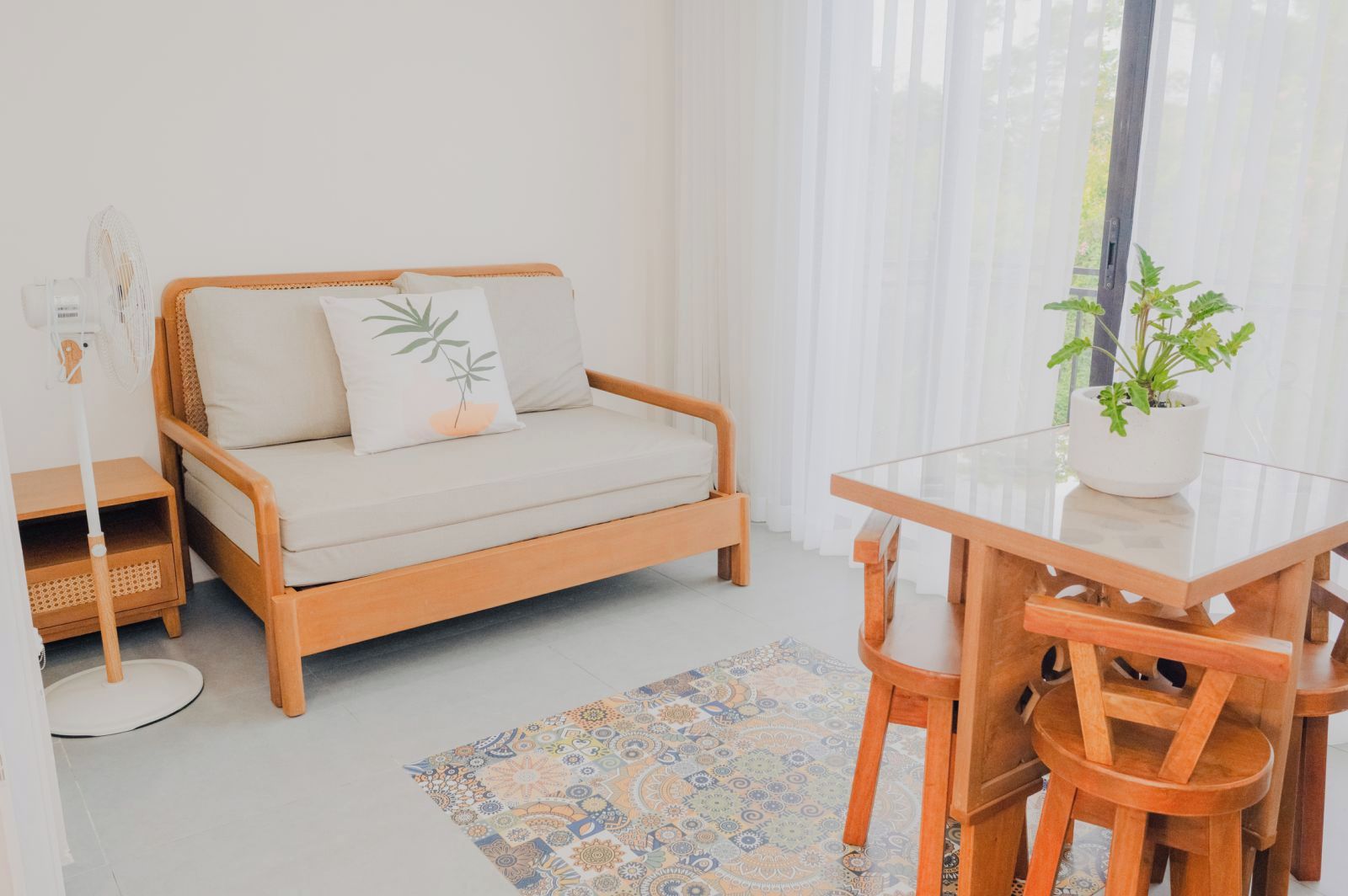 A cozy room with a wooden sofa, a glass dining table, and a potted plant.
