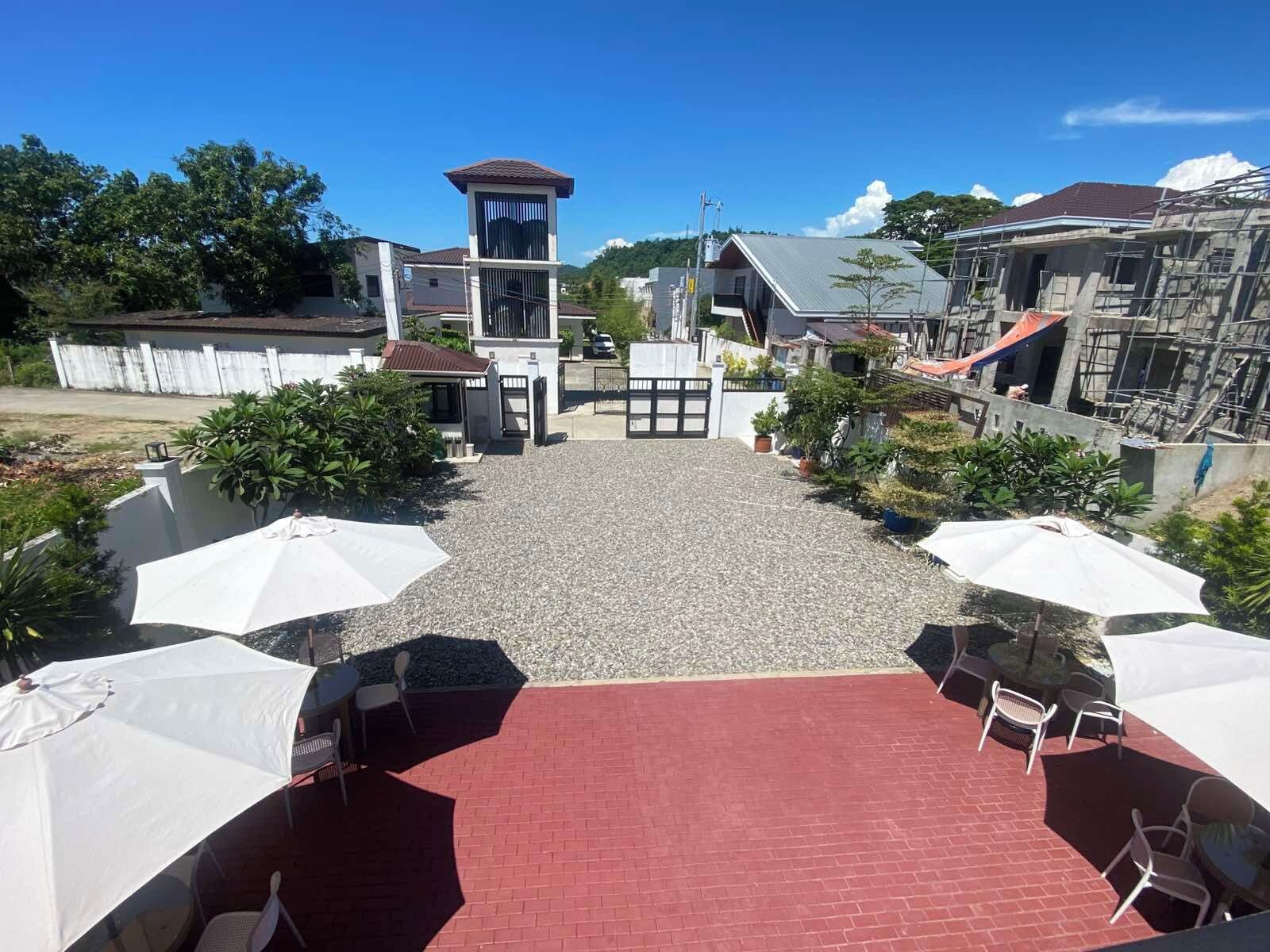 A courtyard with a red brick floor, white umbrellas, and outdoor seating.