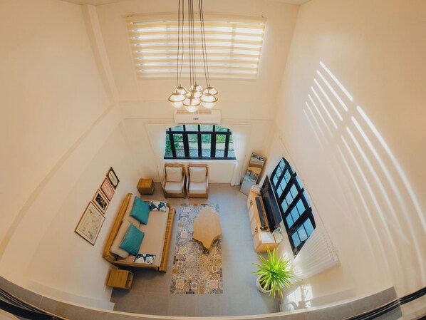 A spacious living area with a sofa set, a coffee table, a TV, and a potted plant.