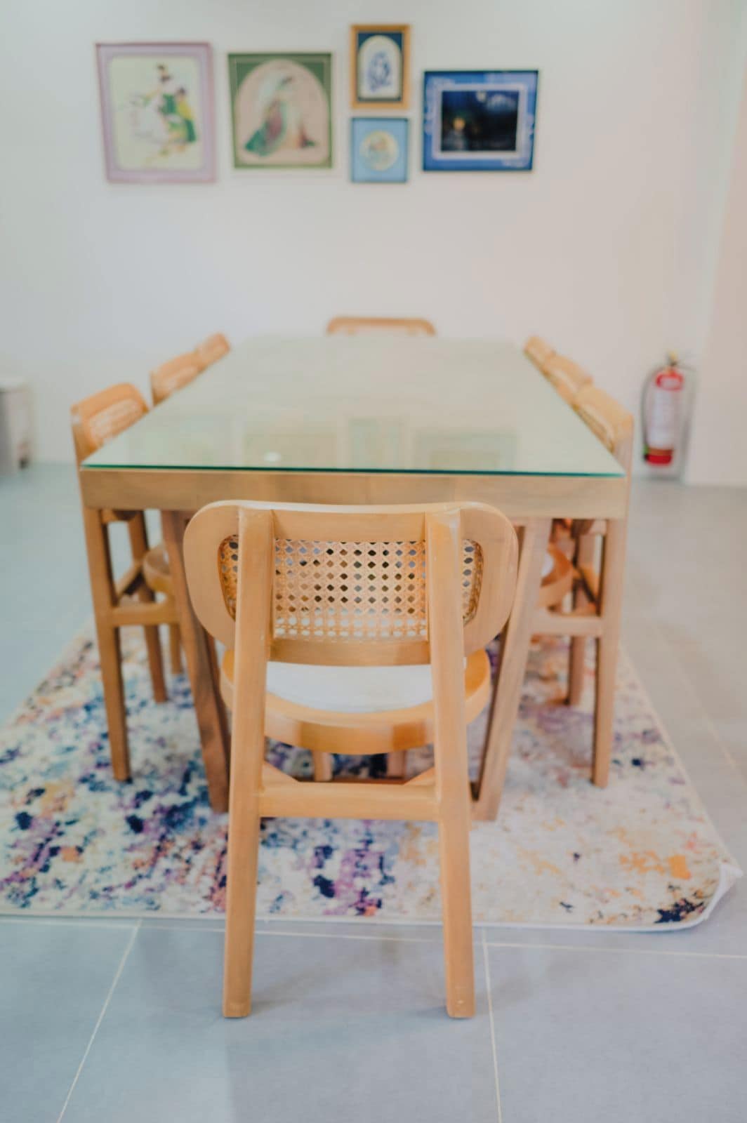 Una mesa de comedor con sillas, un tablero de vidrio y una alfombra estampada con flores.