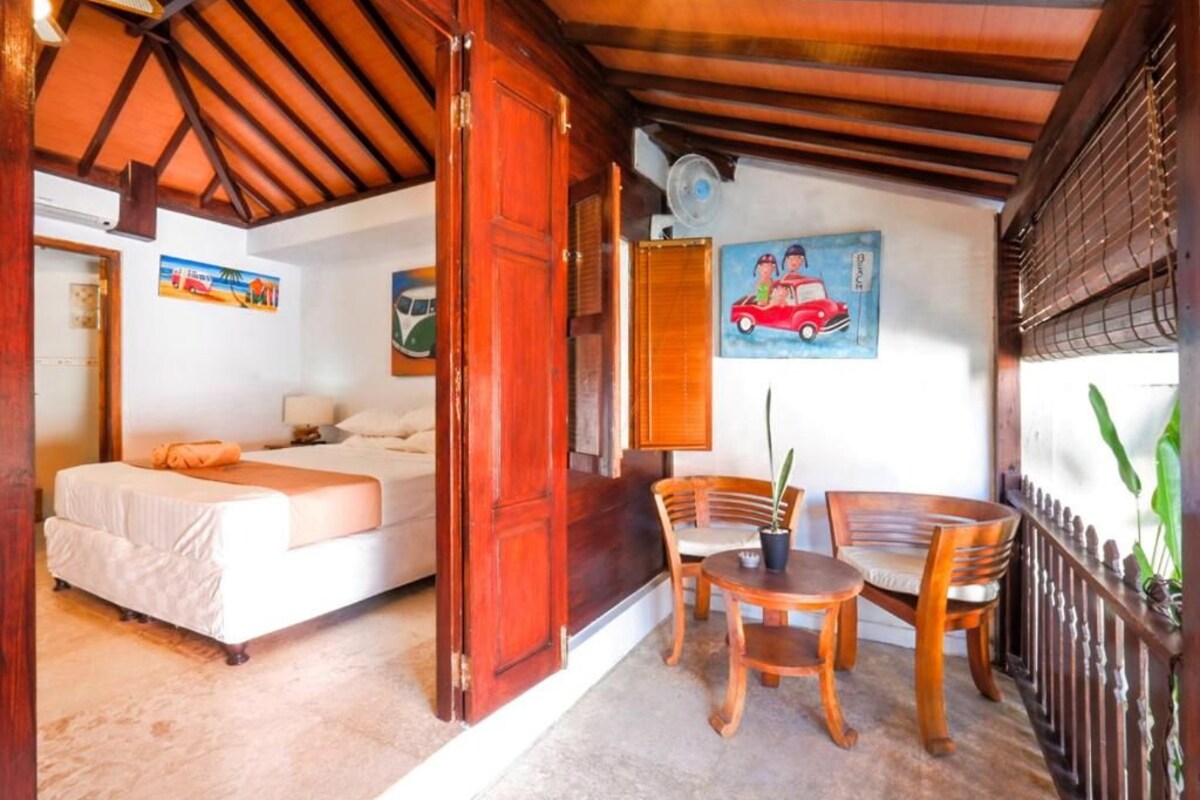 Une pièce avec un lit, une table et des chaises, et un tableau accroché au mur.