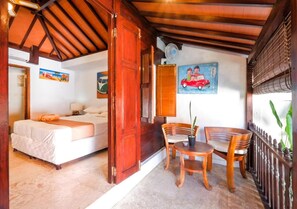 Une pièce avec un lit, une table et des chaises, et un tableau accroché au mur.