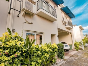 A residential building with a balcony, a car parked in the driveway, and lush greenery in the foreground. - Surfer Paradise Villas Bali (Pererenan)