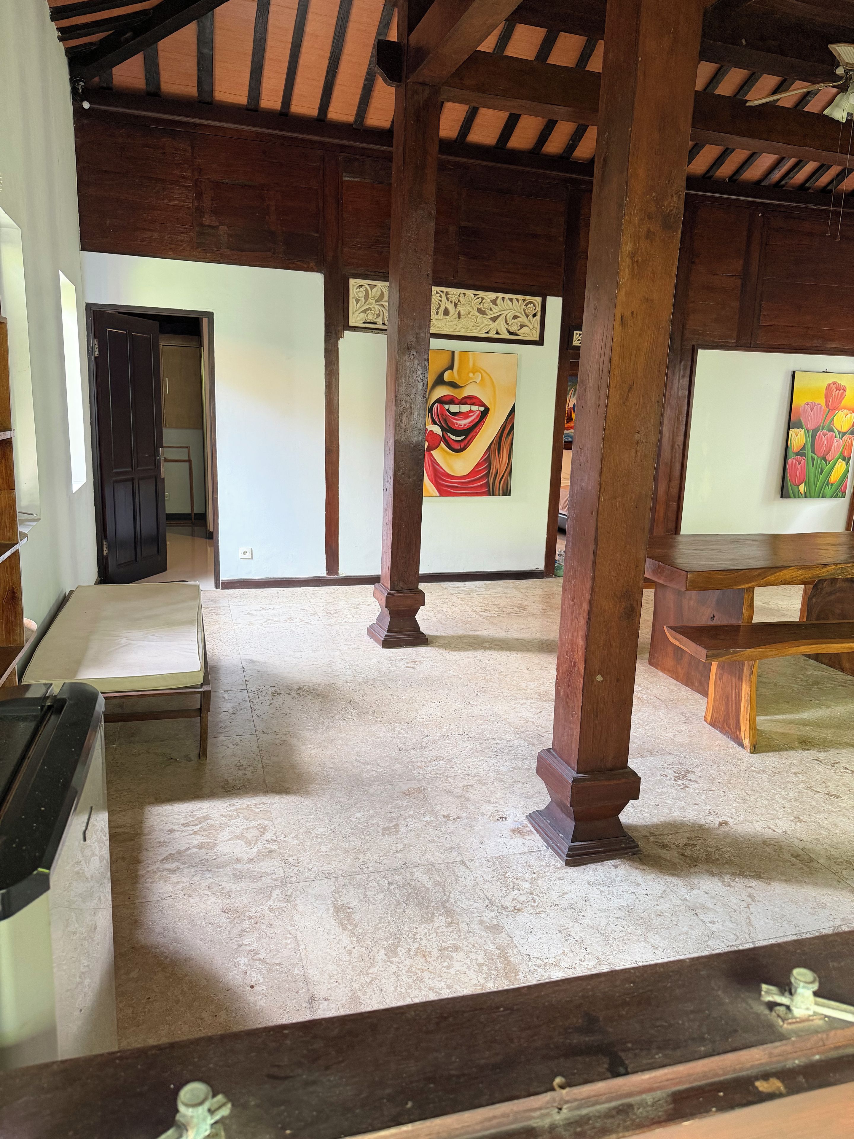 Una habitación con techo alto, vigas de madera, una cama, un escritorio y un cuadro en la pared.