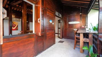 Un interior de madera con un mostrador de recepción, un área de comedor con una mesa y sillas, y un ventilador de techo.