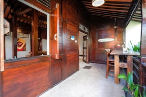 A wooden interior with a reception desk, a dining area with a table and chairs, and a ceiling fan. - Surfer Paradise Villas Bali (Pererenan)