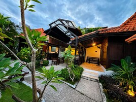 A courtyard with a covered seating area, a small garden, and a building with a tiled roof.