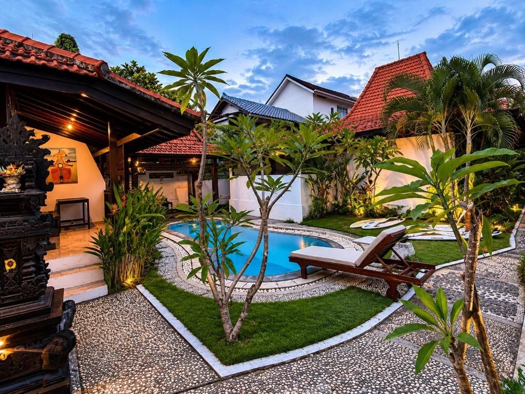 A pool area with a lounge chair, surrounded by tropical plants and a small garden.